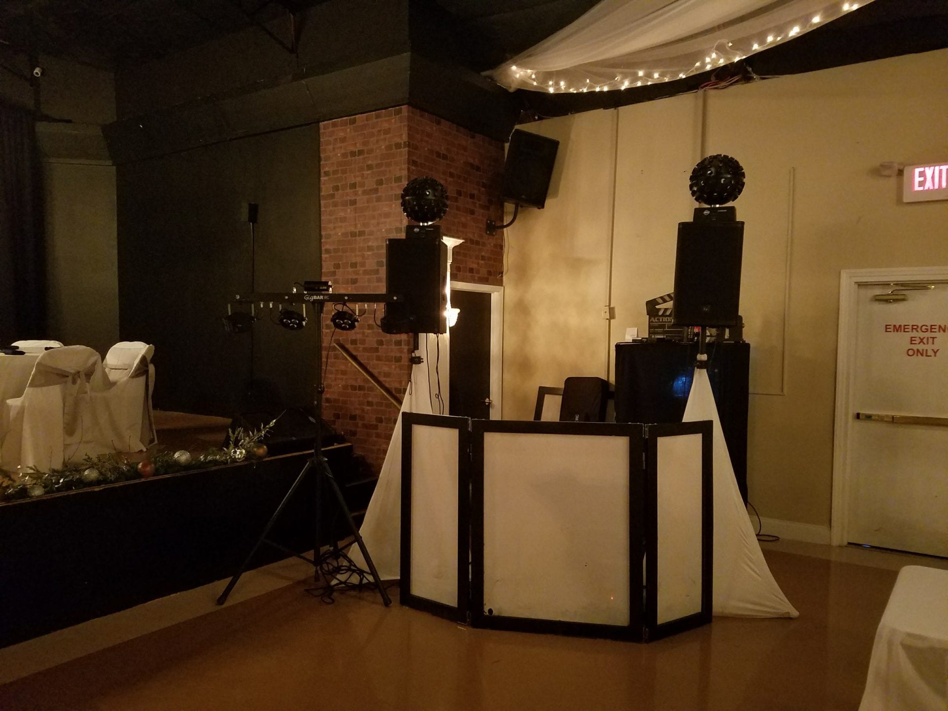 A room with two white speakers and a dj booth.